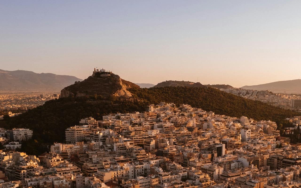 Lycabettus hill glowing over Athens rooftops at golden hour